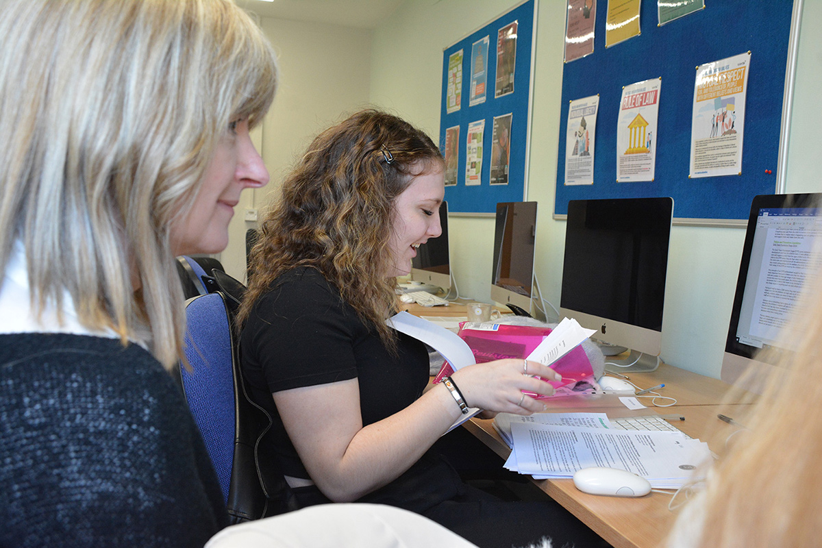 Learner t a computer being supported by a member of staff