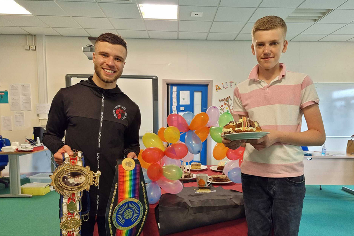 Learner holding a cake standing with a trainer holder boxing belts