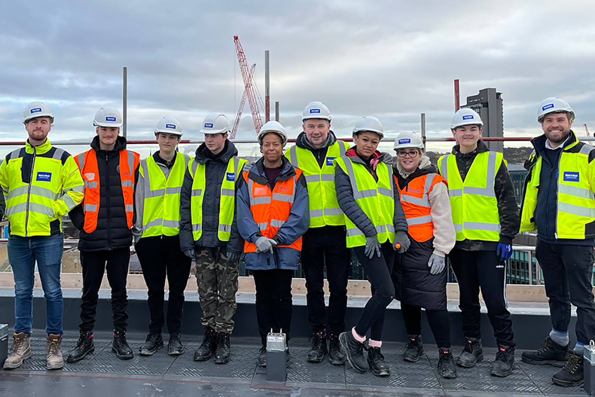 Students and volunteers wearing hi vis and helmets, lined up on a rooftop