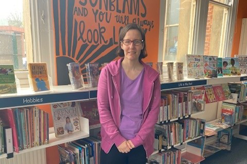 Anna stood in front of some bookshelves in a library