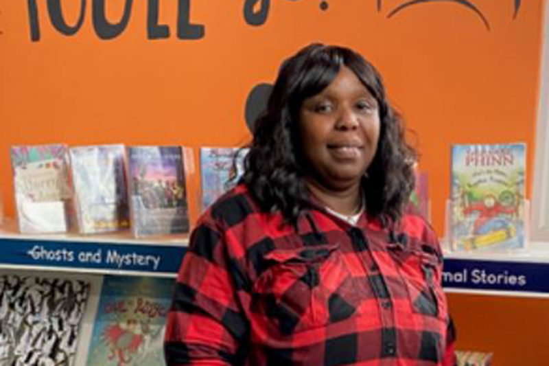 Christina stands next to a bookshelf smiling